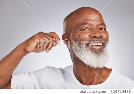 Cotton bud, cleaning ear and senior black man happiness portrait for grooming hygiene, self care and cosmetics earwax removal in white studio background. Elderly african model, smile and ears cleaner 129713488