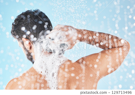 Shower, water and man with soap for cleaning, washing and hygiene on blue background in studio. Grooming, bathroom and back of male with foam, sponge and water splash for skincare, wellness and spa Shower, water and man with soap for cleaning, washing and hygiene on blue background in studio. Grooming, bathroom and back of male with foam, sponge and water splash for skincare, wellness and spa 129713496