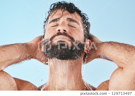 Face, water splash and man in shower for skincare in studio isolated on a blue background. Dermatology, water drops and male model cleaning, bathing or washing for healthy skin, hygiene and wellness. Face, water splash and man in shower for skincare in studio isolated on a blue background. Dermatology, water drops and male model cleaning, bathing or washing for healthy skin, hygiene and wellness. 129713497