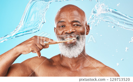 Black man, dental hygiene and toothbrush with water, wellness and hygiene against blue studio background. Oral health, African American male and mature guy with smile, toothpaste and clean mouth. 129713520