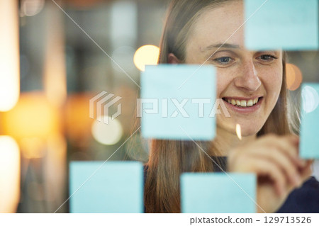 Planning, strategy and woman writing on glass wall sticky note, brainstorming idea for creative startup agency. Market research, goals and target ideas, designer at workshop with mindmap for business 129713526