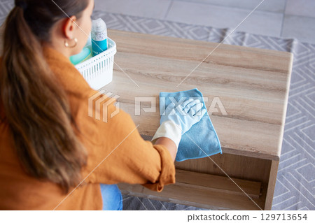 Woman, cleaning and cloth for table in home living room with product, polish or shine on wood. Domestic hygiene expert, wipe and basket to clean in lounge for coffee table, house furniture and focus 129713654