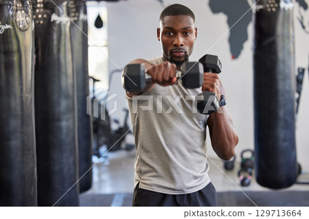 Portrait, dumbbell and fitness with a black man bodybuilder in a gym for a workout or exercise. Health, training or weightlifting with a male athlete or personal trainer exercising in a sports center 129713664