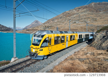 Yellow Bernina Express train traveling along lake Bianco 129713908
