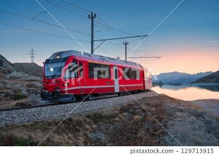 Bernina Express train near Lake Bianco in Switzerland at sunset 129713915
