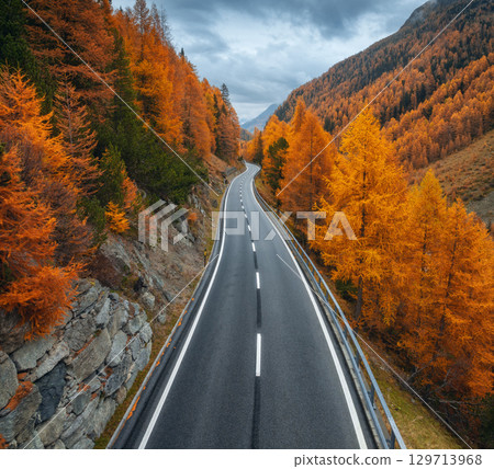 Aerial view of winding mountain road and orange forest in autumn Aerial view of winding mountain road and orange forest in autumn 129713968