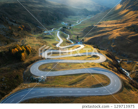 Aerial view of winding mountain road, river in alpine valley 129713975