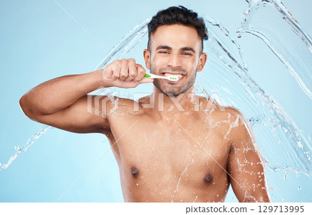 Face, water splash and man with toothbrush for cleaning in studio on blue background. Dental veneers, hygiene and portrait of happy male model brushing teeth for oral wellness, health or fresh breath Face, water splash and man with toothbrush for cleaning in studio on blue background. Dental veneers, hygiene and portrait of happy male model brushing teeth for oral wellness, health or fresh breath 129713995