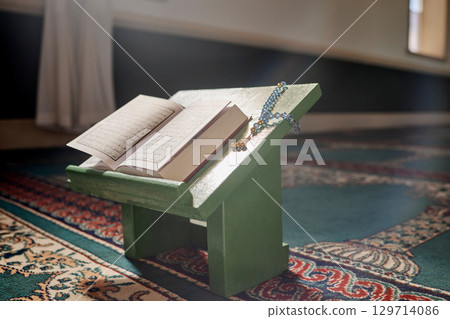 Quran, prayer beads and mosque with an open book and a rosary in an empty holy room or temple ready for praying. Islamic misbaha, tasbih or sibha and scripture in a muslim place of worship for eid 129714086