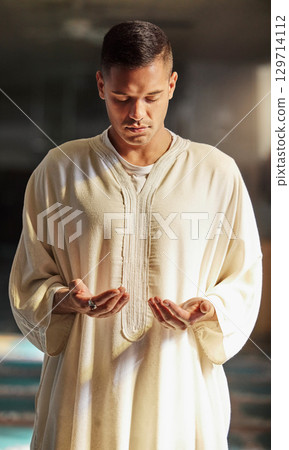 Man, muslim faith and praying in mosque for God, peace and mindfulness with traditional islamic clothes. Islam worship, prayer and spiritual balance for ramadan, religion and gratitude in Doha, Qatar 129714112
