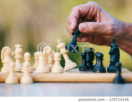 Chess, play or hand with a king on a board game with a winning strategy in a tournament outdoors in nature. Checkmate, mindset or smart man playing in a sports contest or problem solving challenge 129714246