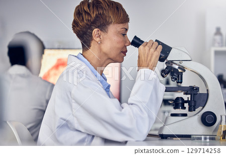 Science, laboratory and black woman with microscope, research for vaccine development. Healthcare, medical innovation and senior scientist woman in hospital lab looking at pharmaceutical test results 129714258