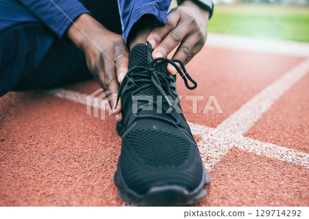 Sports, feet and man with ankle pain from exercise, workout and marathon training in stadium. Fitness, runner and shoes of athlete with joint strain, injury and arthritis from running on field track 129714292
