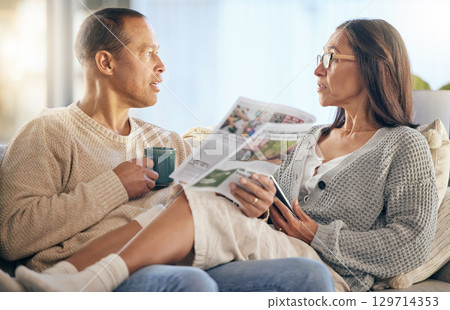 Senior couple, newspaper and relax talking on sofa reading, morning conversation or quality time bonding together in living room. Elderly man, woman and news discussion, coffee and retirement peace 129714353