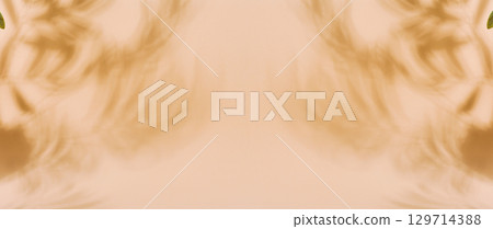 Blurred shadows of palm leaves are cast across a solid light brown background Blurred shadows of palm leaves are cast across a solid light brown background 129714388