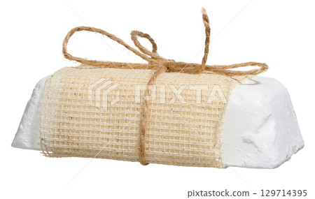 A bar of white handmade soap wrapped in a coarse mesh fabric made from natural fibers and tied with twine in a bow. A bar of white handmade soap wrapped in a coarse mesh fabric made from natural fibers and tied with twine in a bow. 129714395