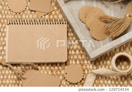 Blank notepad and various craft supplies made of recycled paper and twine on a woven mat. DIY, handcrafted goods 129714534