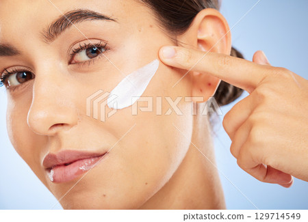Portrait, skincare and moisturizer with a model woman in studio on a gray background for antiaging beauty. Face, lotion and product with an attractive young female inside to apply facial treatment 129714549