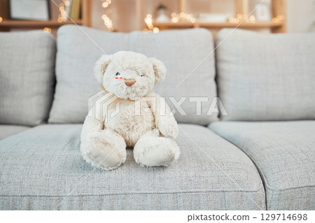 Teddy bear, child toy and baby toys on a living room sofa for a christmas or birthday present. Soft, furry and children bear on a home lounge couch with no people and holiday gift with bokeh lights 129714698