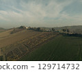Scenic countryside landscape showing cultivated fields and vineyards covering rolling hills in autumn light. 129714732