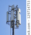 Multiple antennas and electronic equipment are installed on a telecommunication tower, enabling wireless communication under a clear blue sky 129714753