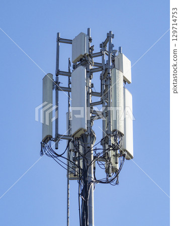 Multiple antennas and electronic equipment are installed on a telecommunication tower, enabling wireless communication under a clear blue sky 129714753