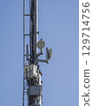 Telecommunication tower against a clear blue sky, featuring antennas, microwave dishes, and electronic equipment, symbolizing modern communication infrastructure 129714756