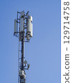 Cellular base station tower with antennas and microwave dishes providing wireless communication services against a clear blue sky ensures seamless connectivity 129714758