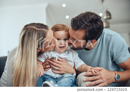 Mom, dad and baby kiss on sofa in living room of happy family home, young parents and child together. Love, happiness and couple kissing kid with smile while sitting on couch in New York apartment. Mom, dad and baby kiss on sofa in living room of happy family home, young parents and child together. Love, happiness and couple kissing kid with smile while sitting on couch in New York apartment. 129715029