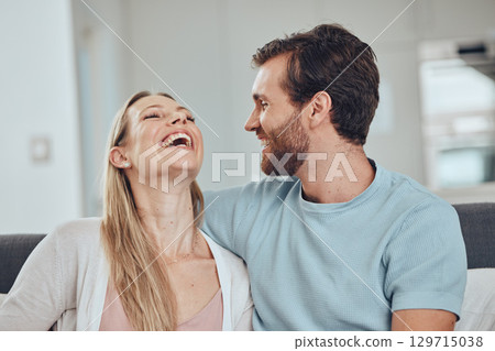 Couple, laughing and home of a woman and man in a living room with love, happiness and care. House, relax and funny joke of a happy couple on a house sofa smile about bonding and marriage together Couple, laughing and home of a woman and man in a living room with love, happiness and care. House, relax and funny joke of a happy couple on a house sofa smile about bonding and marriage together 129715038