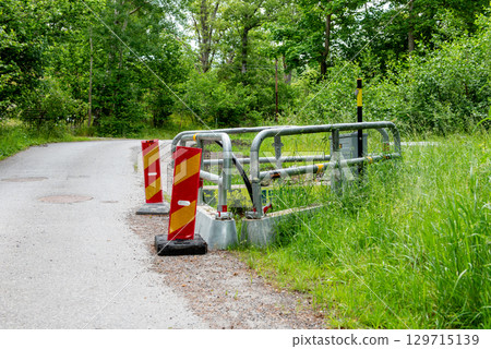 Work site closed with barriers and sign for roadworks. 129715139