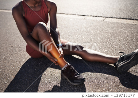 Leg, injury and pain with a sports black woman holding her ankle outdoor during a fitness workout from above. Ankle, sprain or exercise with a female runner or athlete suffering from an injured joint 129715177
