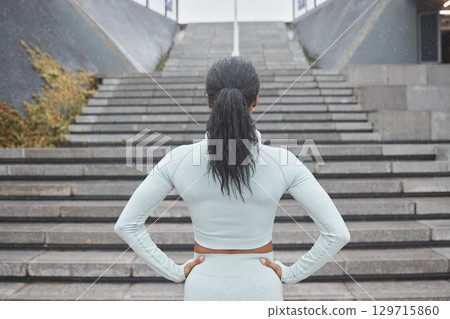 Stairs, running and black woman runner fitness ready for workout and steps training with motivation. Back view of a woman before wellness exercise, sports and athlete challenge for a healthy body Stairs, running and black woman runner fitness ready for workout and steps training with motivation. Back view of a woman before wellness exercise, sports and athlete challenge for a healthy body 129715860