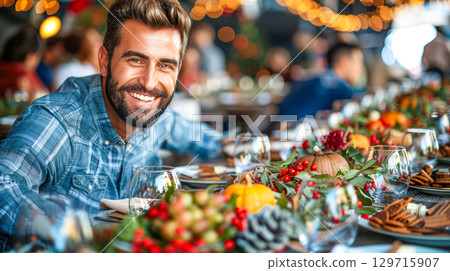 Smiling man in plaid shirt at festive dining table with autumn decorations and warm ambiance 129715907