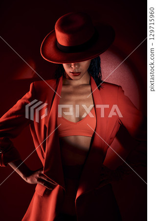 Woman, fashion hat and spotlight for suit, sexy and mystery in studio for beauty, punk aesthetic and cosmetics. Fashion model girl, cyberpunk design or unique with dark cosmetic by red background Woman, fashion hat and spotlight for suit, sexy and mystery in studio for beauty, punk aesthetic and cosmetics. Fashion model girl, cyberpunk design or unique with dark cosmetic by red background 129715960
