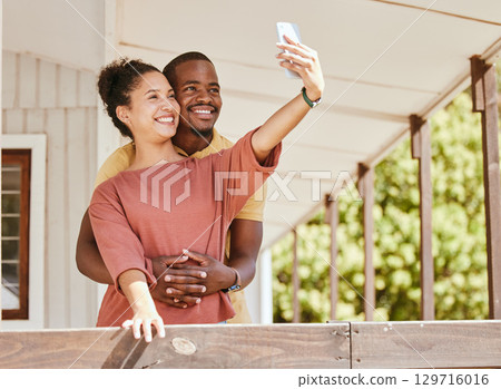 Love, phone selfie and black couple in home by balcony, bonding and having fun. Romance, hug and man and woman taking pictures on mobile smartphone for happy memory, social media or profile picture. 129716016