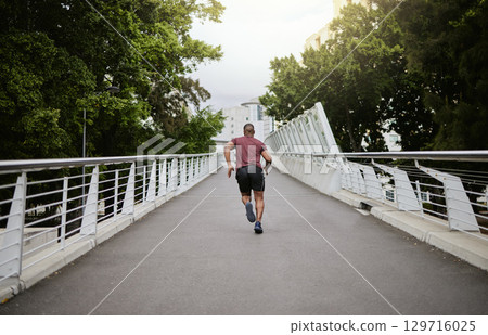 Fitness, man and running in the city park for healthy exercise, cardio workout or training in the outdoors. Active athletic male runner in sports activity, run or exercising outside on city bridge 129716025