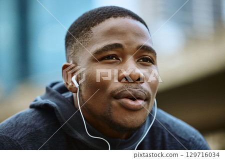 Face, music earphones and black man in city streaming radio or podcast on break after exercise. Sports, fitness and male from Nigeria listening to workout song while thinking of running in winter. Face, music earphones and black man in city streaming radio or podcast on break after exercise. Sports, fitness and male from Nigeria listening to workout song while thinking of running in winter. 129716034