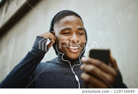 Music, phone and running with black man in city for streaming, podcast and mobile radio. Workout, health and cardio with face of runner with earphones by wall for training, sports and endurance 129716040