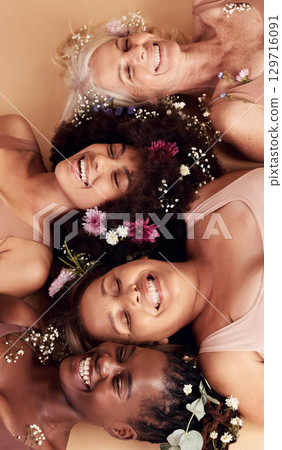 Top view, women diversity or faces with flowers on studio background in empowerment, divine feminine energy or self love. Smile, happy or skincare beauty models with plants, leaf or organic spa glow 129716091