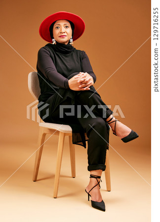 Muslim woman, studio background chair or fashion hat in luxury style, trend or classy clothes with empowerment or self love mindset. Portrait, confident or mature islamic model in designer clothing Muslim woman, studio background chair or fashion hat in luxury style, trend or classy clothes with empowerment or self love mindset. Portrait, confident or mature islamic model in designer clothing 129716255
