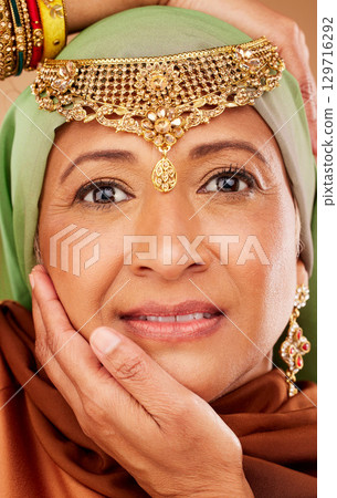 Face, beauty and jewelry on egyptian woman with hands on face for arab culture with hands on face for fashion and skincare. Portrait of a mature muslim female from Egypt with makeup and cosmetic Face, beauty and jewelry on egyptian woman with hands on face for arab culture with hands on face for fashion and skincare. Portrait of a mature muslim female from Egypt with makeup and cosmetic 129716292