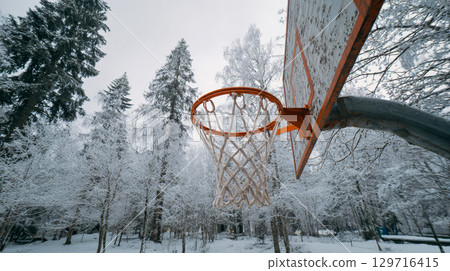 Village basketball hoop in snowy forest, winter sports in nature 129716415