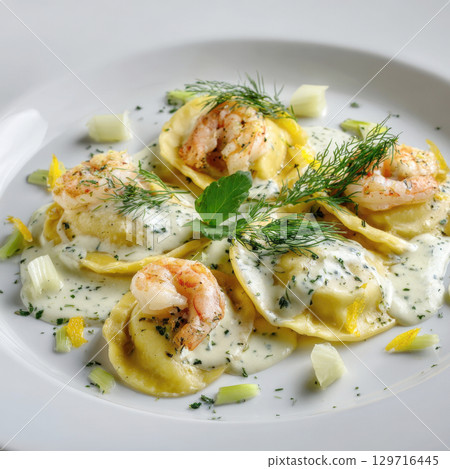 A close-up of delicate ravioli pasta filled with shrimp and dill, served in a rich white wine and lemon cream sauce. The dish is garnished with fresh herbs and lemon zest 129716445