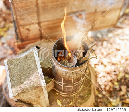 Smoke, fire and metal container on bee farm for agriculture, smoking and honey production. Farming, vintage and beekeeping with flame in smoker to calm bees for safety, protection and preparation 129716539