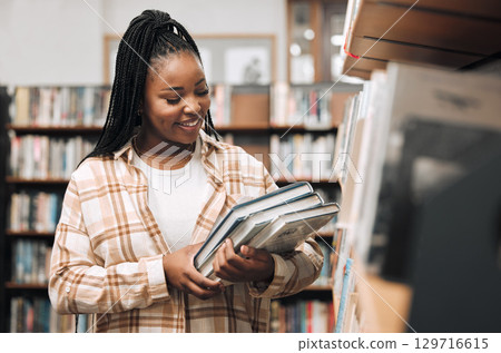 Black woman, university student and library with books for education, learning and knowledge at campus. Happy, smile and gen z college student at bookshelf for studying, academic research and reading 129716615