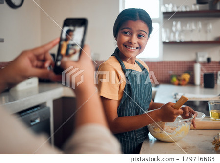 Baking, girl and phone picture of a child cooking in home kitchen with a proud smile about learning. Happy, cooking development and kid in a house helping to make cookies with mom and mobile photo Baking, girl and phone picture of a child cooking in home kitchen with a proud smile about learning. Happy, cooking development and kid in a house helping to make cookies with mom and mobile photo 129716683