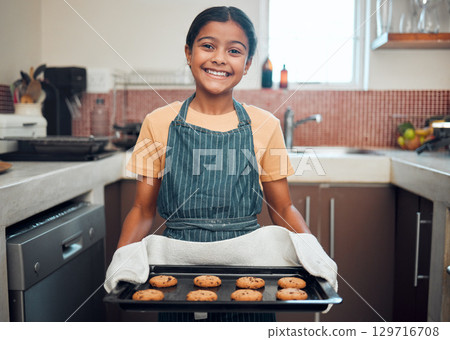 Baking, cookies and girl portrait happy about food, learning and youth helping in the kitchen and home. Cooking, house and child baker with a proud smile and happiness from making a kid dessert 129716708