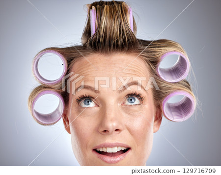 Hair, rollers and beauty with a model woman in studio on a gray background for a hairstyle using curlers. Hair care, thinking and face with an attractive young female styling her curly extensions 129716709