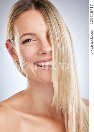 Beauty, hair care and woman blonde, healthy and shine for wellness, soft or volume on grey studio background. Portrait, female and girl with clean, keratin and scalp treatment with smile or cosmetics 129716717